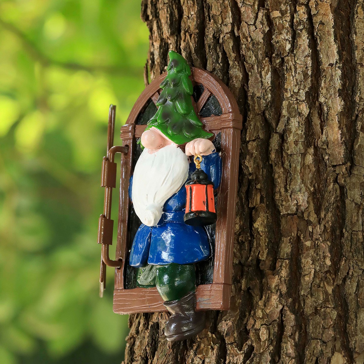 Gnome window statue fixed to a tree trunk in a green garden