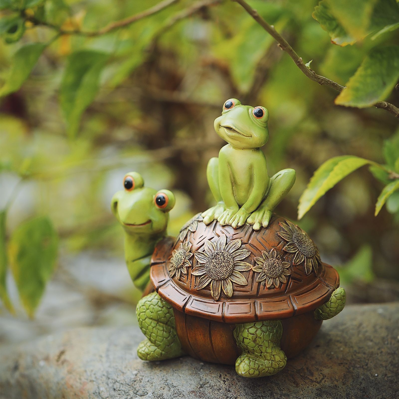 Turtle and frog garden figurine set among green leaves outdoors