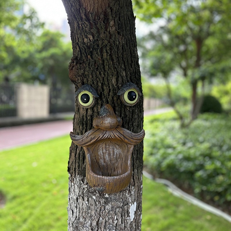Tree face decoration mounted on a trunk in a green lawn