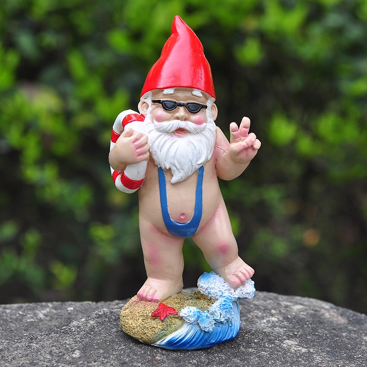 Gnome figurine resting on a rock beside green foliage
