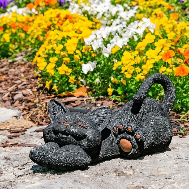 Resin cat figurine placed in a garden setting with a playful stance