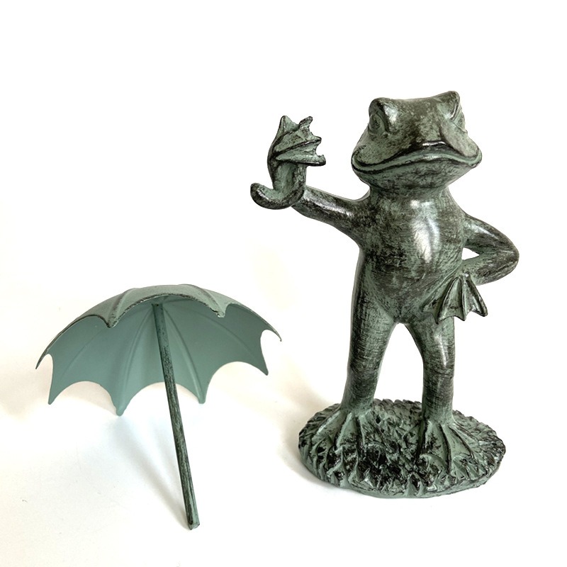 Frog ornament beside its detached umbrella showing the pole and underside