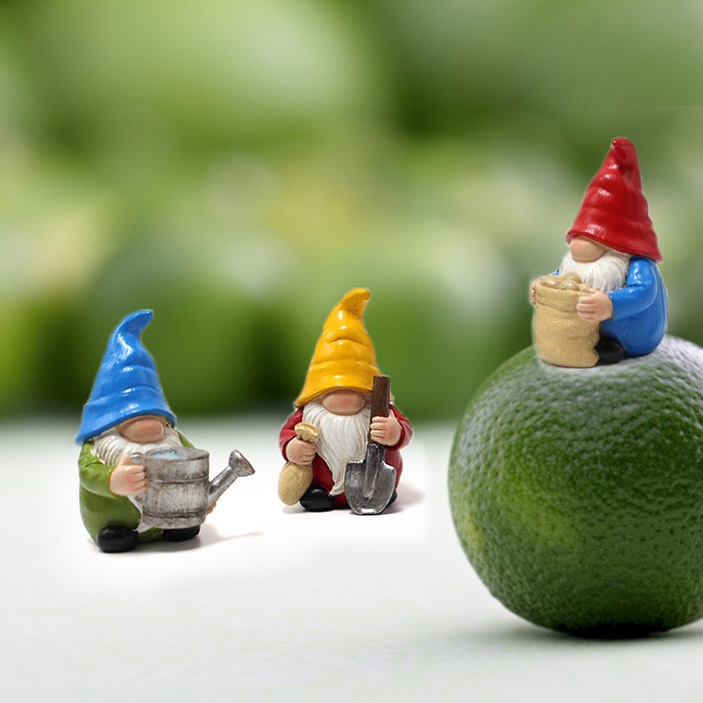 Three small gnomes beside a lime in a bare garden corner