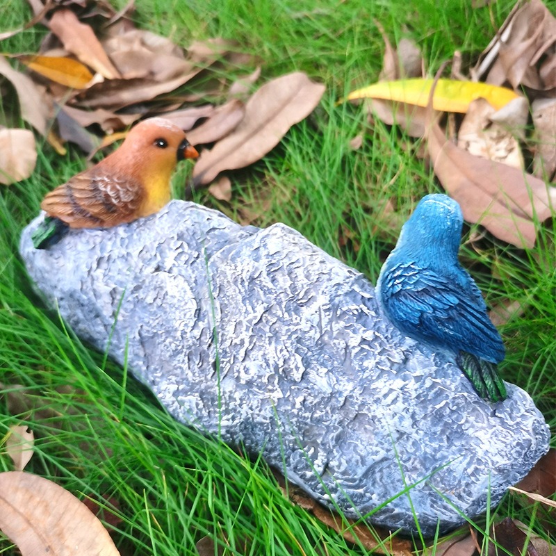 Side view of the welcome stone with a brown and a blue painted songbird