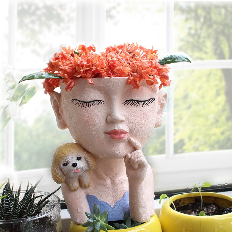 Face planter with orange ixora flowers on a sunny windowsill beside other potted plants