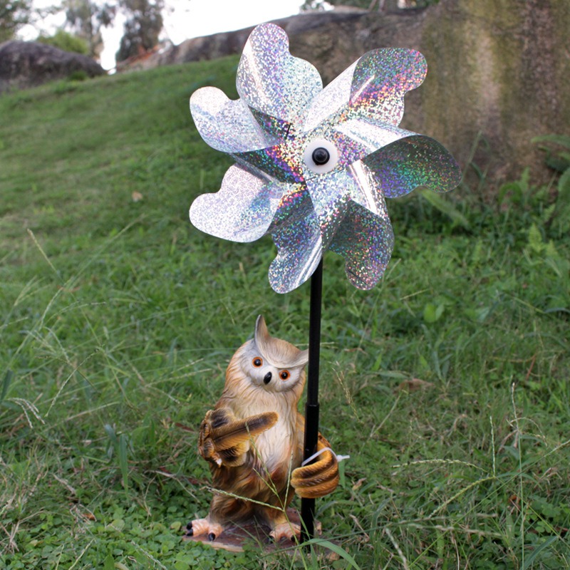 Owl garden decor with holographic silver pinwheel on a metal stake in a grassy lawn