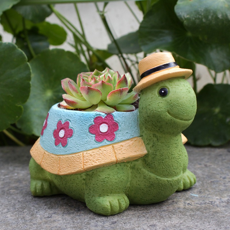 Turtle planter holding a red-tipped succulent outdoors beside green leaves