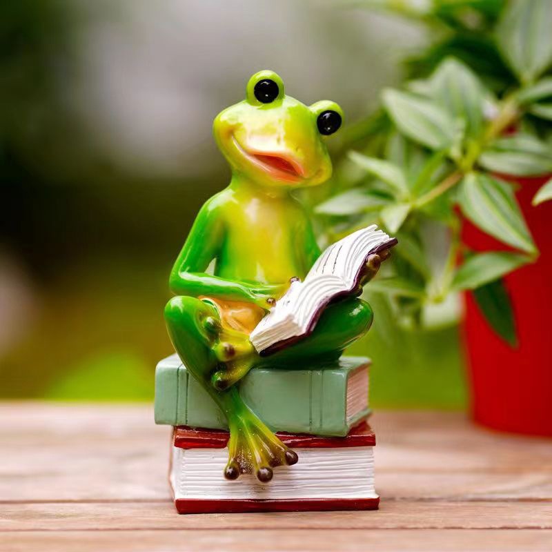 Frog figurine styled among plants on a garden edge as a reading nook