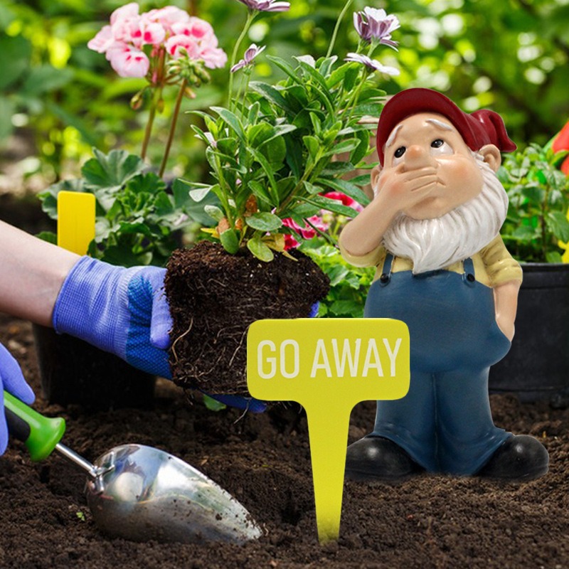 Gnome and GO AWAY sign planted in a working garden bed