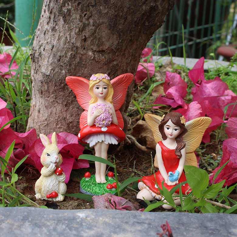 Rabbit and two fairies at the base of a tree trunk with pink flowers