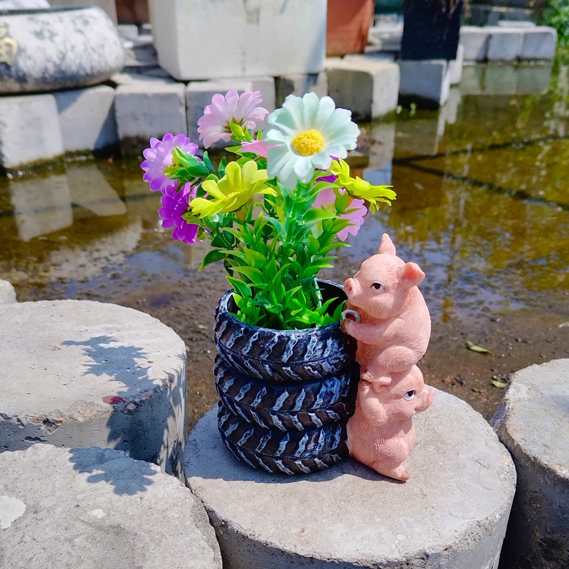Matte black tyre-tread planter standing on a stone block outdoors