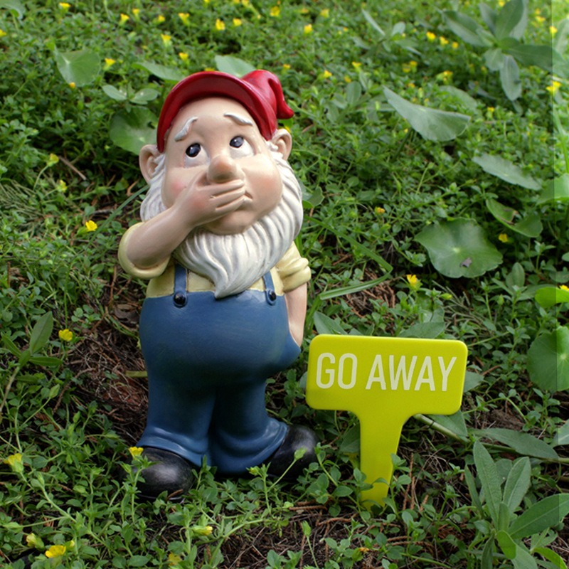 Garden gnome standing on a green lawn beside small yellow flowers