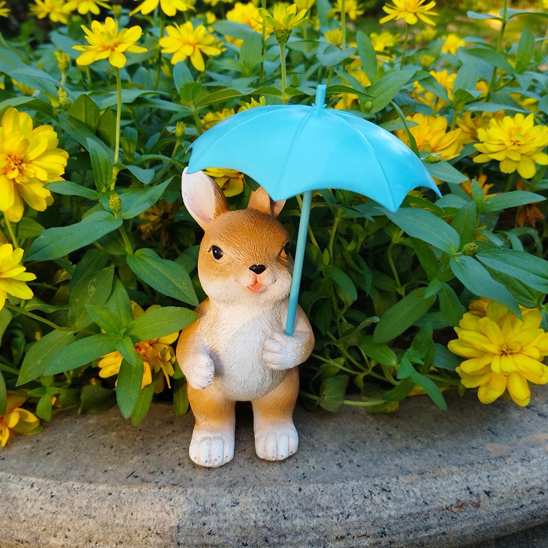 Teal umbrella figurine among green foliage in a garden