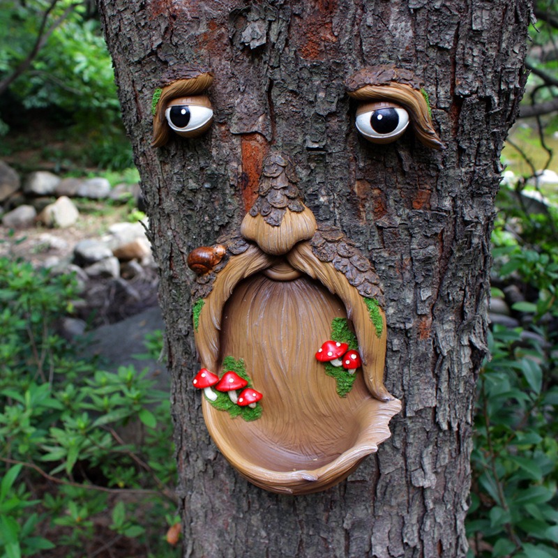 Tree face wall decor mounted on a bare garden tree trunk