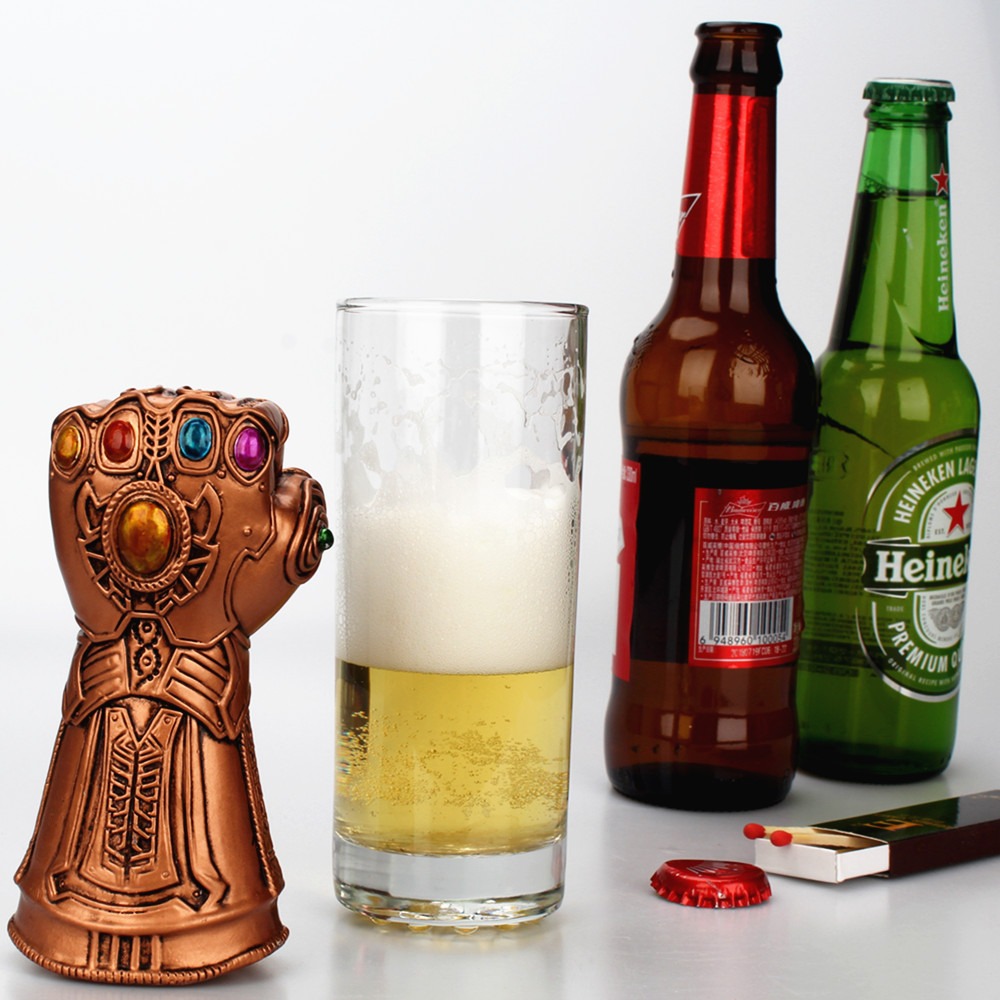 Gauntlet bottle opener beside a glass of beer and bottle caps on a bar table