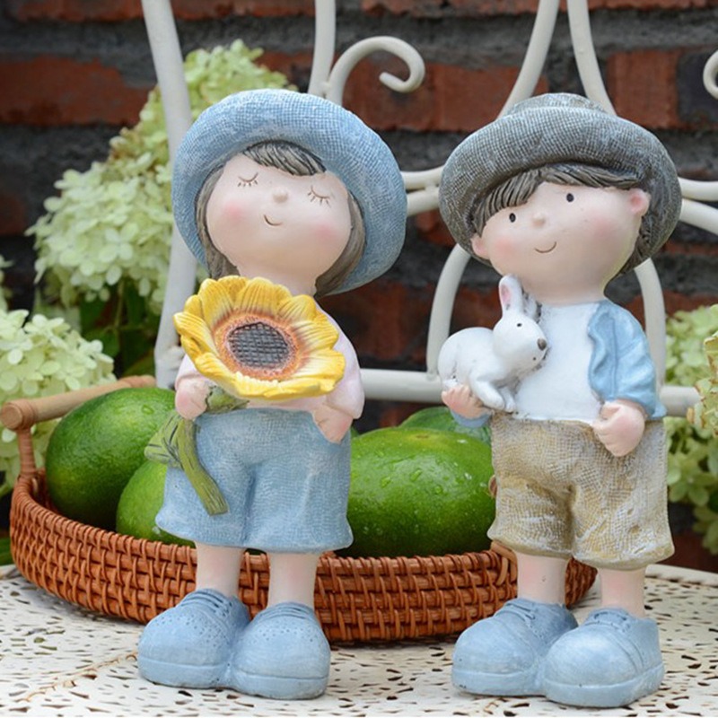 Blue sun hat garden figurines holding a sunflower beside plants