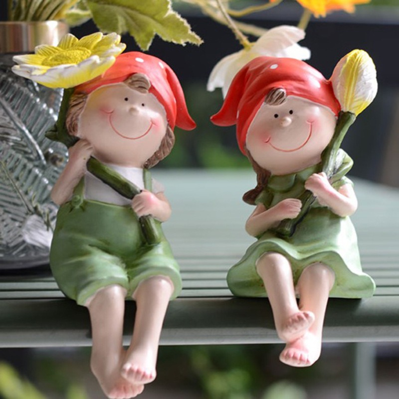 Two red-capped garden figurines seated on a green rail