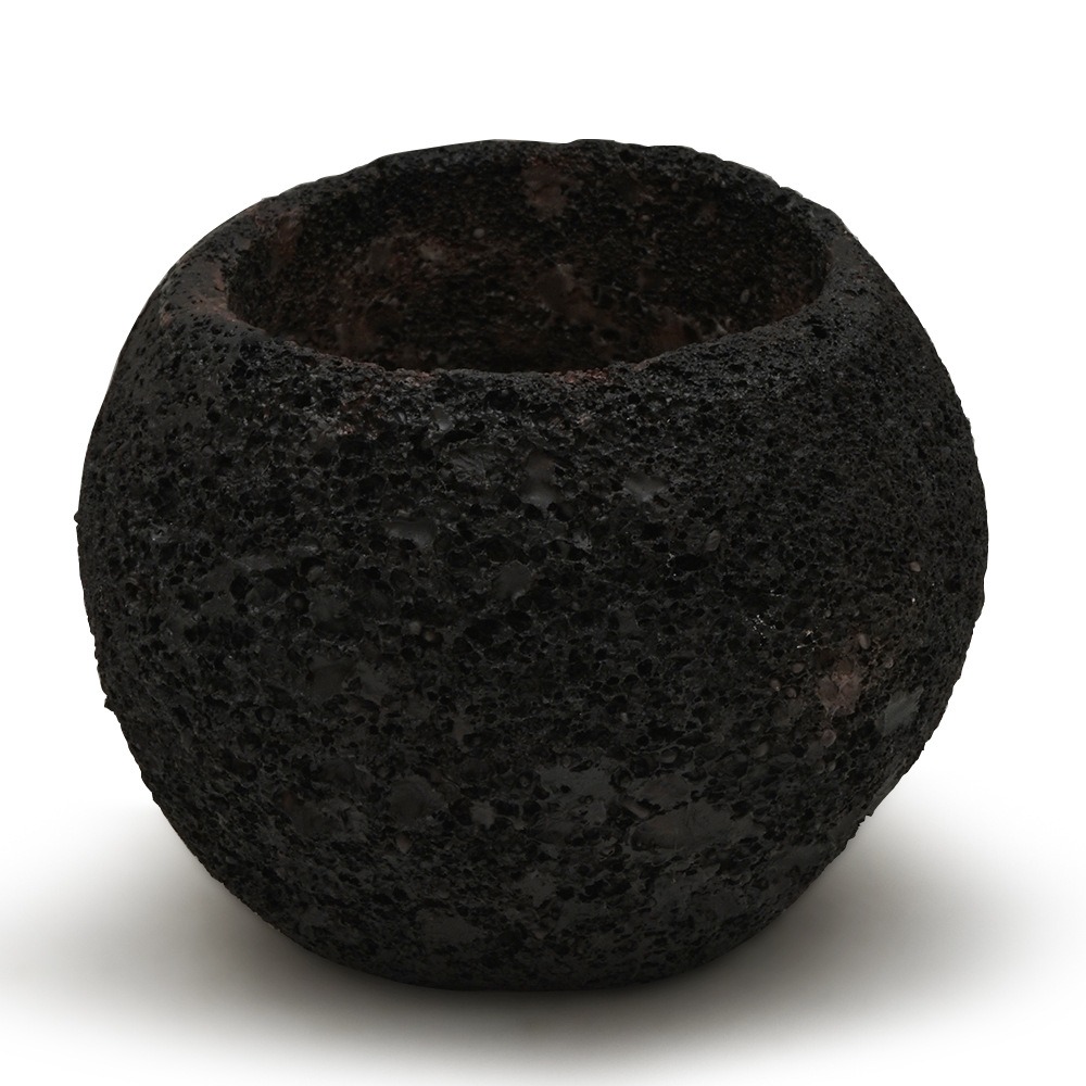 Side view close-up of pitted black volcanic stone planter surface