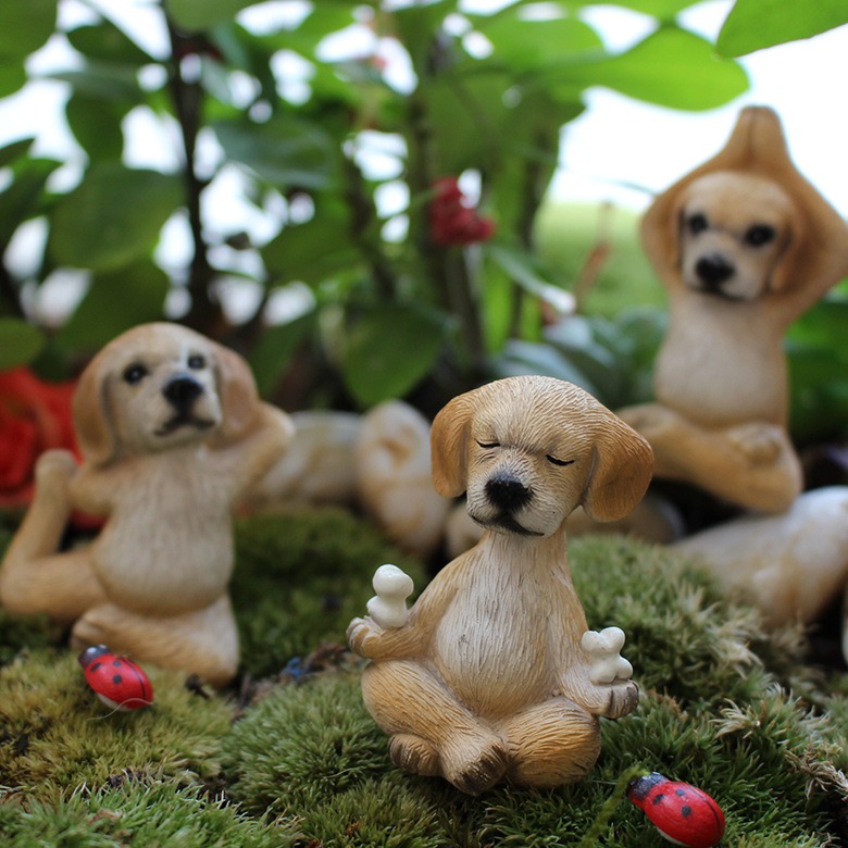 Yoga puppy figurine held in a stretched pose among garden plants