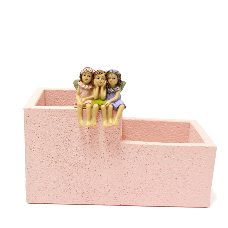 Pink stepped planter with fairy figurines seen from the front in soft light