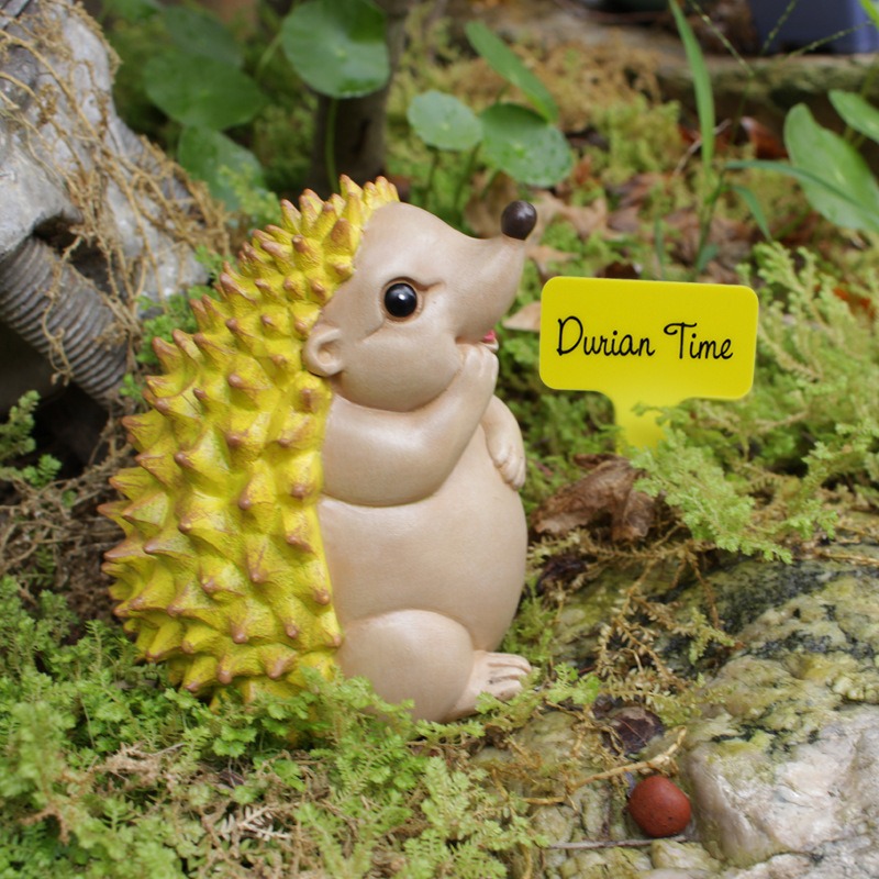Hedgehog figurine among moss and stones in a bare garden bed