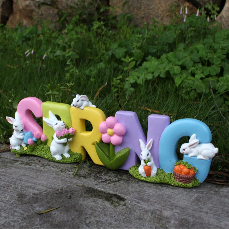 SPRING garden ornament standing on grass with stones behind it