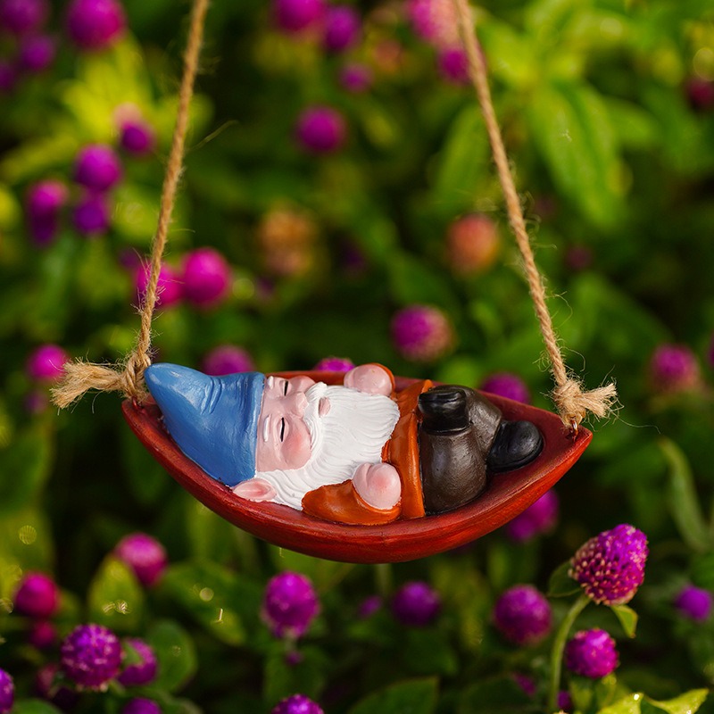 Gnome swing hanging among purple clover blooms and green foliage outdoors
