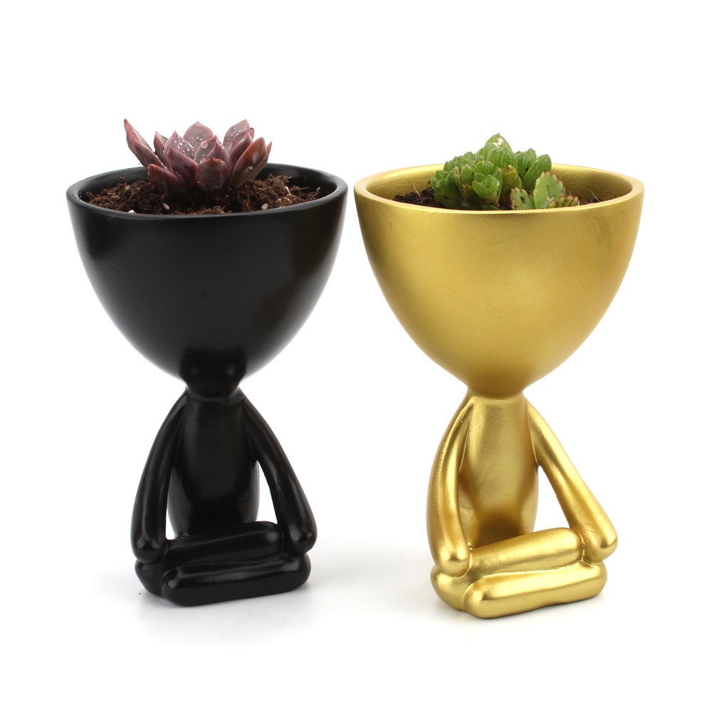 Black and gold figurine planters each holding a live succulent in soil