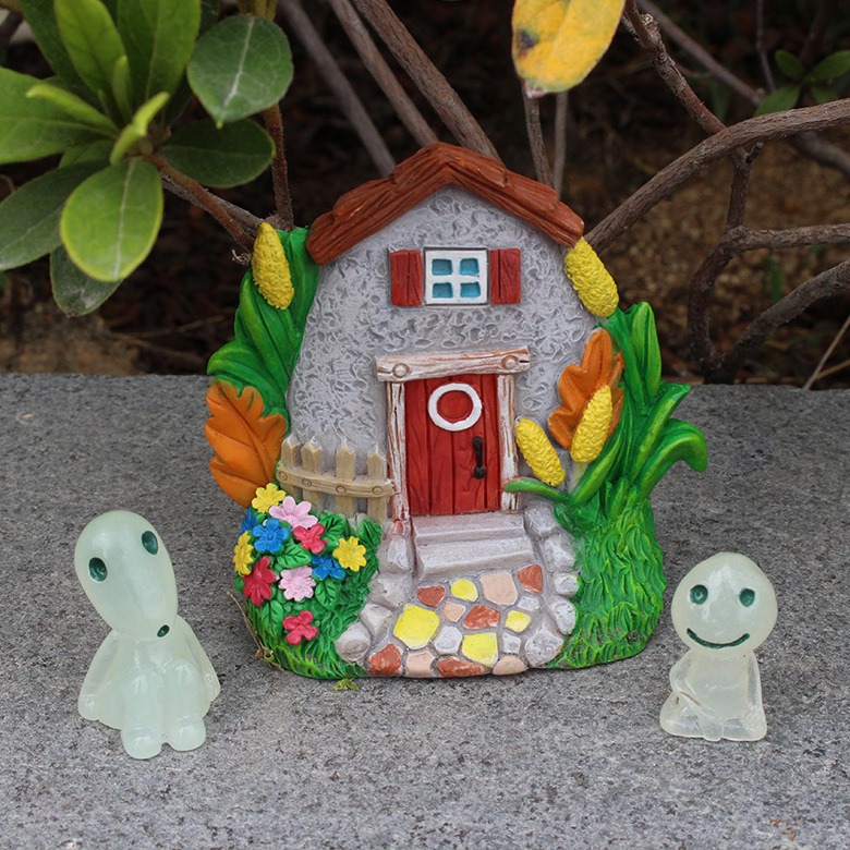 Stone cottage with red door beside flower bed and cobblestone path