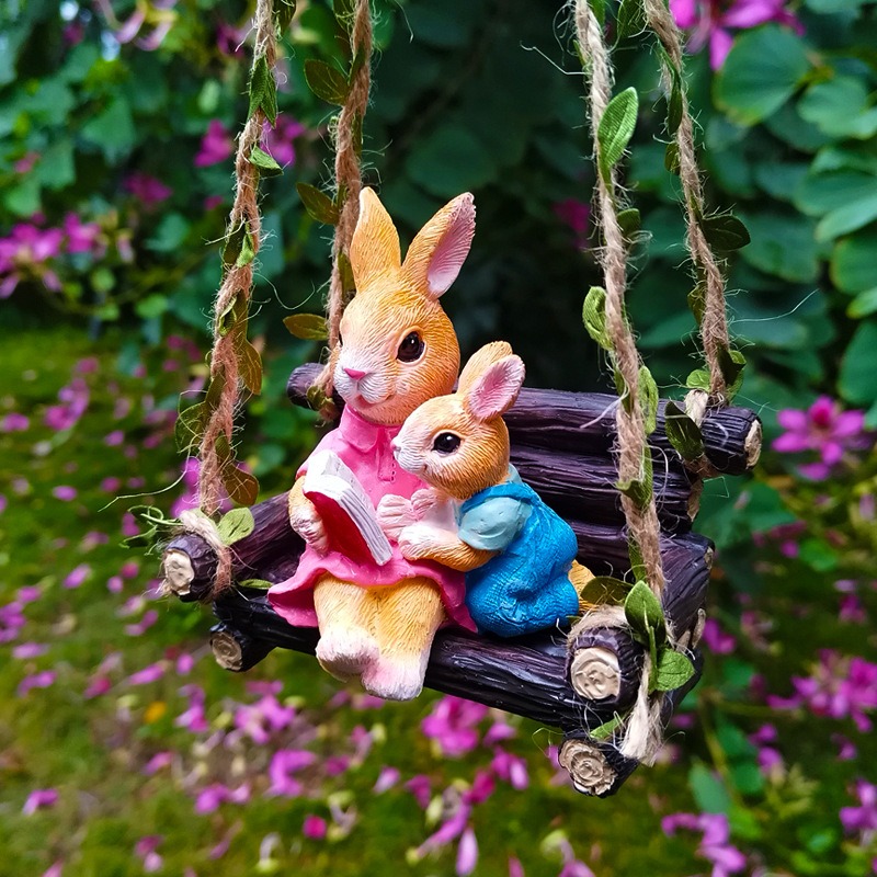 Rabbit reading figurine hung outdoors on a rope swing