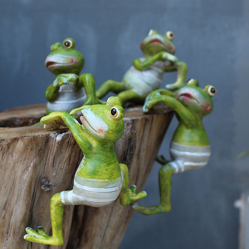 Four resin frogs gripping the rim of a wooden planter