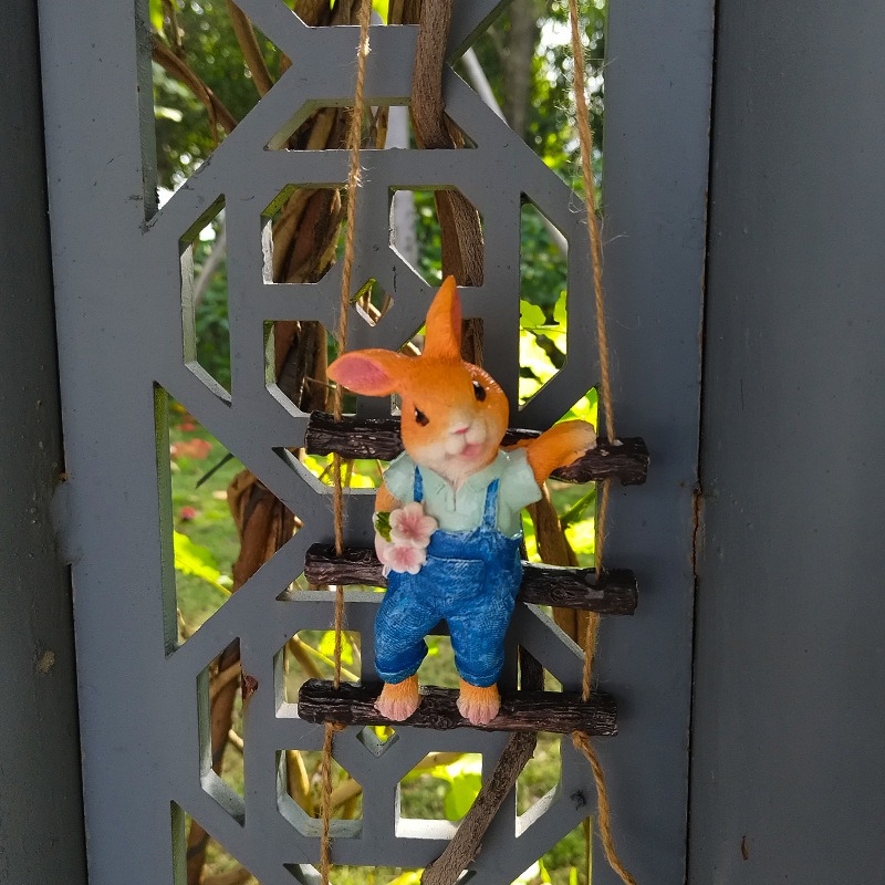 Garden corner with a hanging rabbit ornament on a sunlit fence