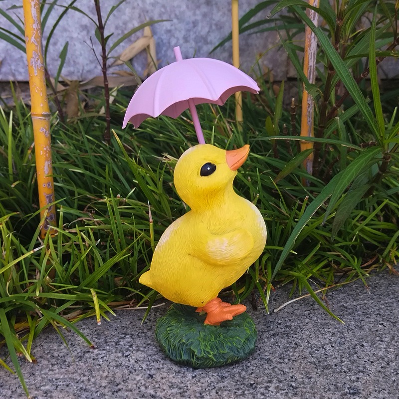 Duckling garden figurine set among green grass and bamboo