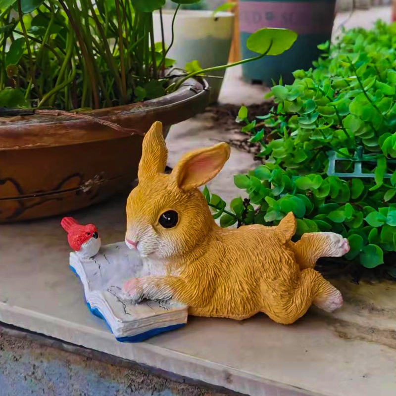 Bunny ornament on a stone patio beside a potted plant and shrubs