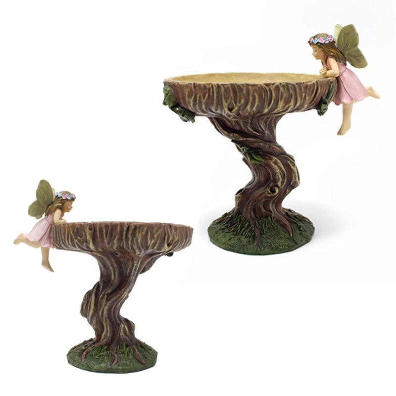 Fairy ornament placed in a garden with a bowl ready for birds