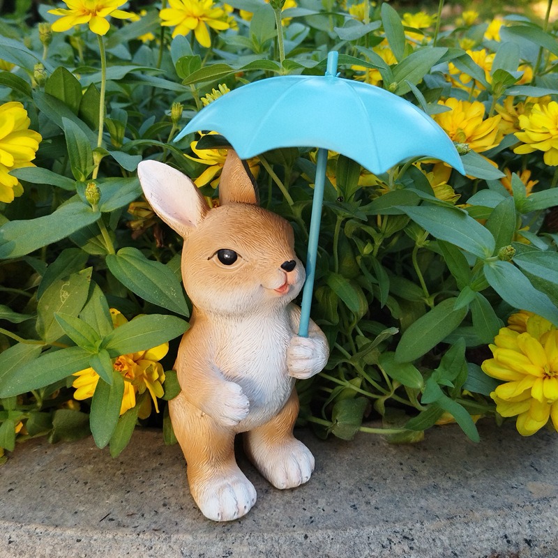 Bunny ornament beside yellow flowers and green leaves on a stone ledge
