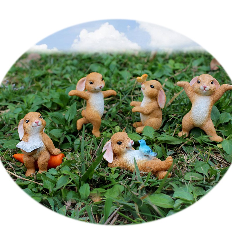 Rabbit figurines placed on grass with a sky backdrop