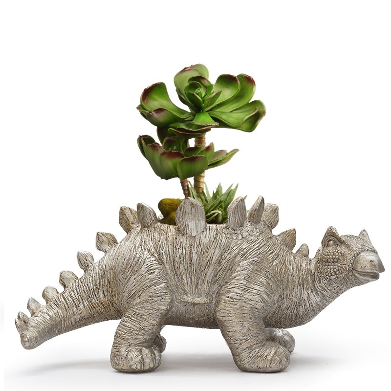 Stegosaurus resin planter finish beside a plant on a desk