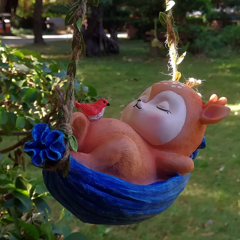Sleeping orange fawn in a blue basket swing hung on a sunny lawn