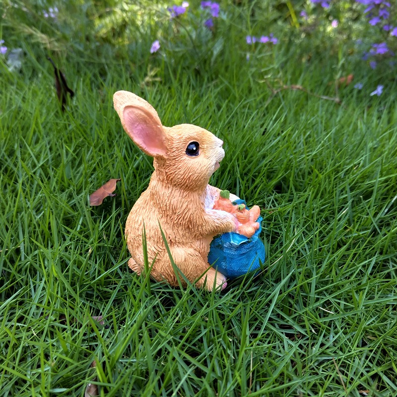 Seated rabbit holding a blue basket of carrots on a green lawn