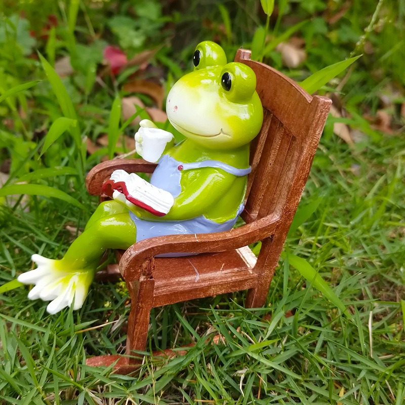 Frog figurine in a wooden chair on grass among leaves
