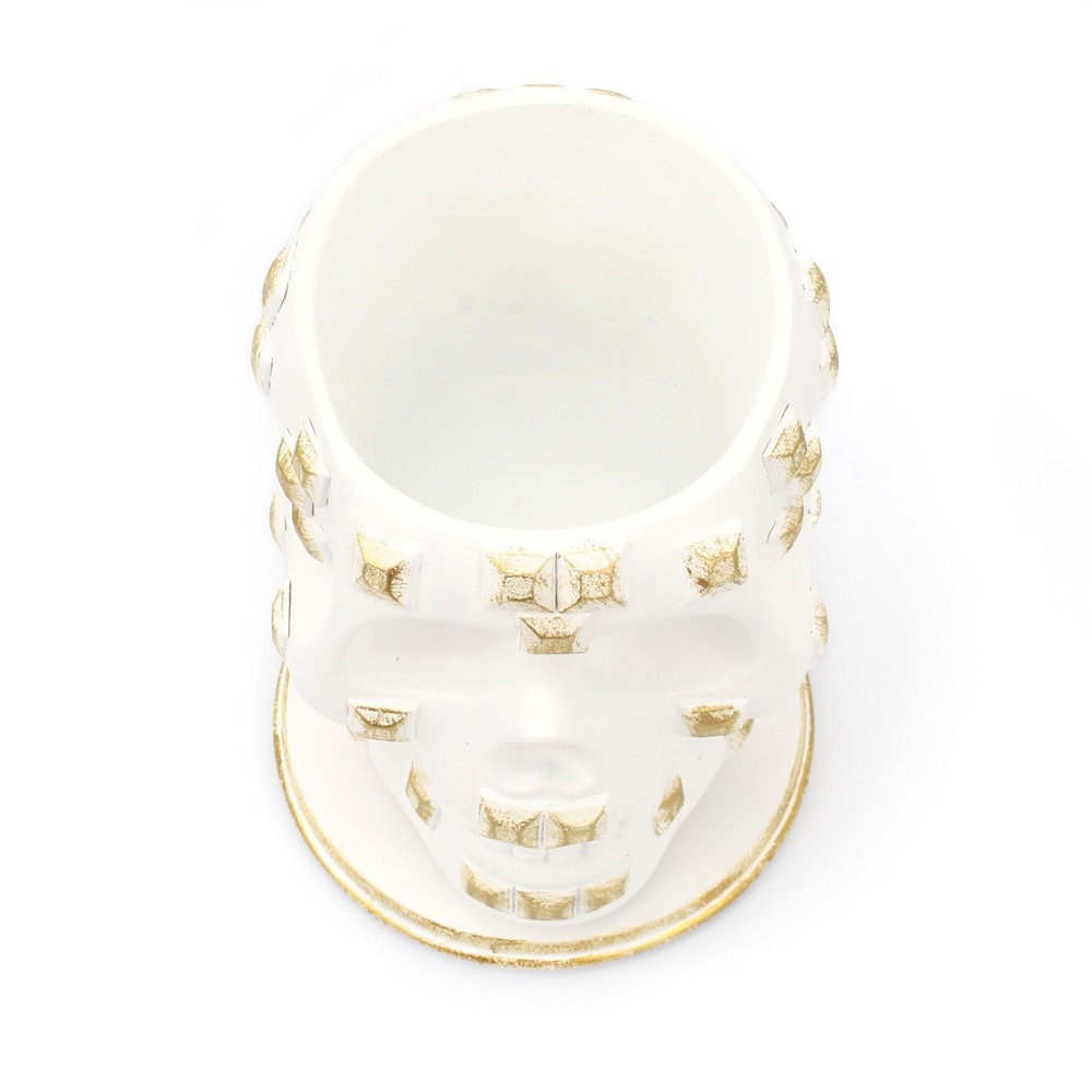 Skull brush holder with teal and purple brushes standing upright on a vanity