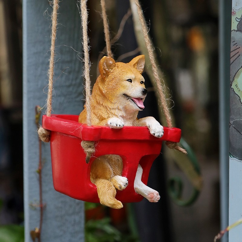 Puppy ornament hanging from a rope in a blurred garden