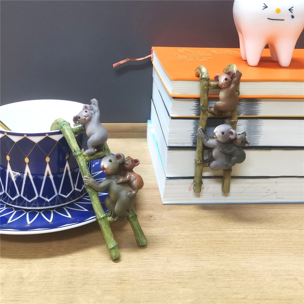 Koala ladder ornament hooked onto a blue and white cup on a stack of books