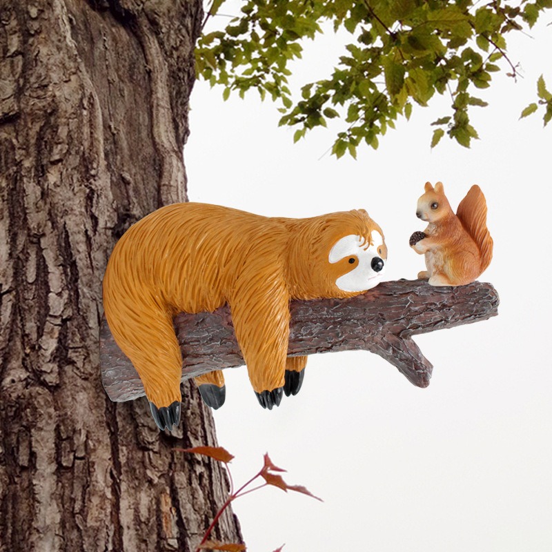 Sloth and squirrel decor mounted on a tree trunk with leafy branches above