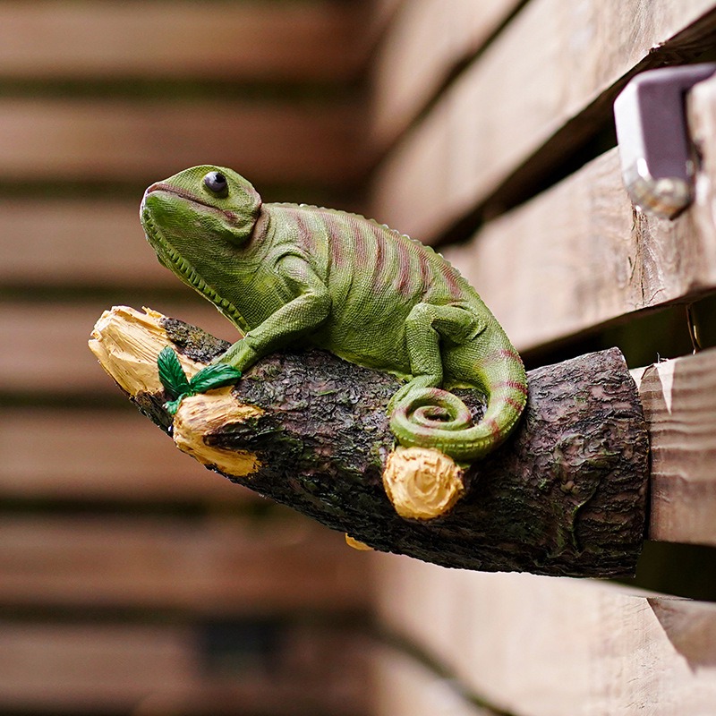 Chameleon ornament clipped to the edge of a wooden fence