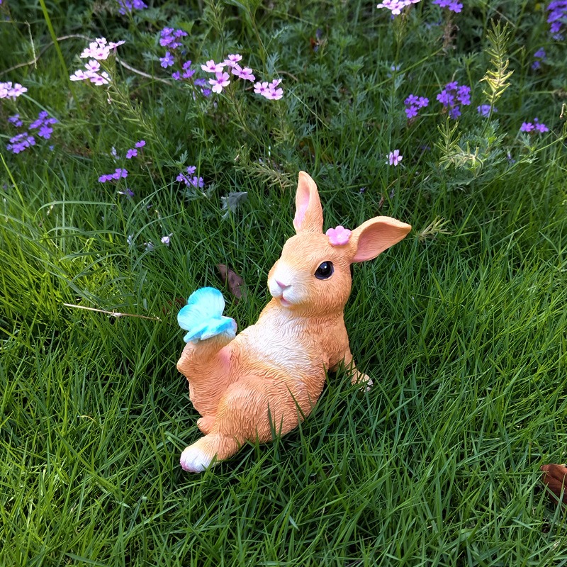 Resin rabbit garden ornament photographed in an outdoor setting