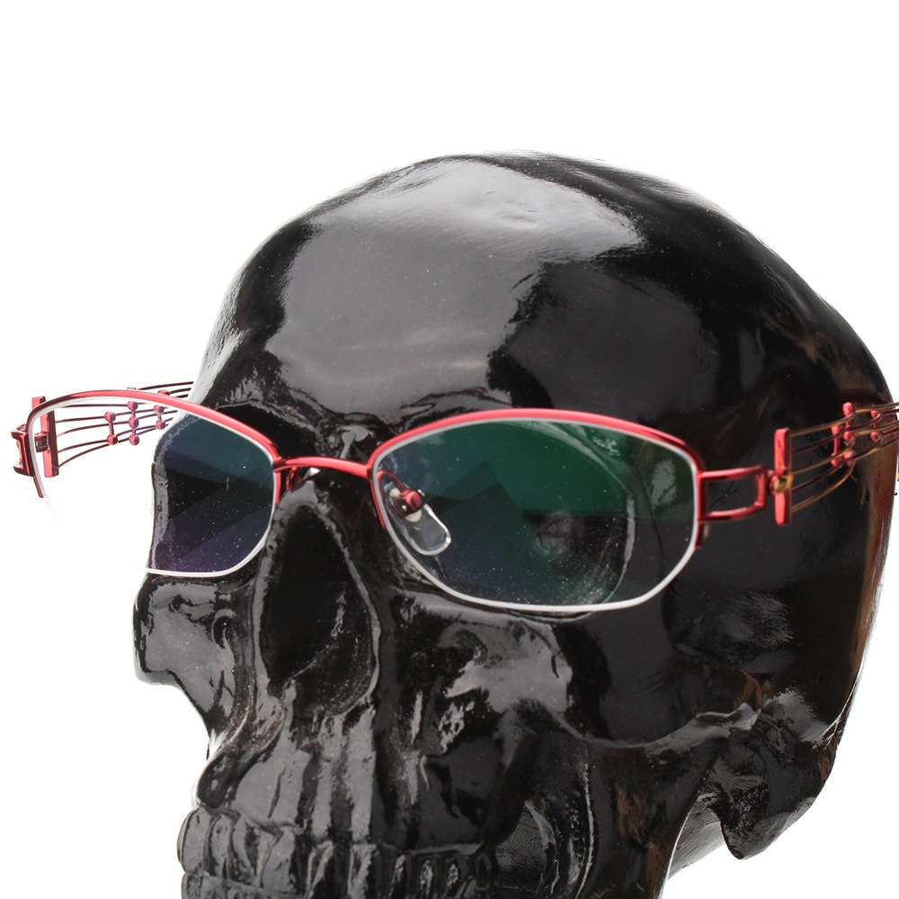 Red wire-frame eyeglasses resting on the black skull stand