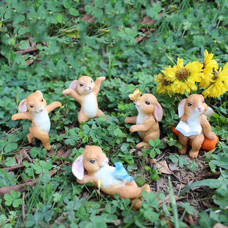 Rabbit figurines beside a carrot and yellow flowers in clover