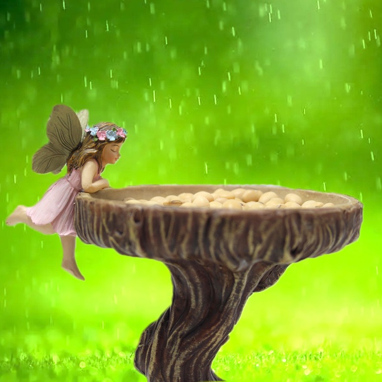 Fairy seated on the rim of a tree-trunk bowl against soft green backdrop